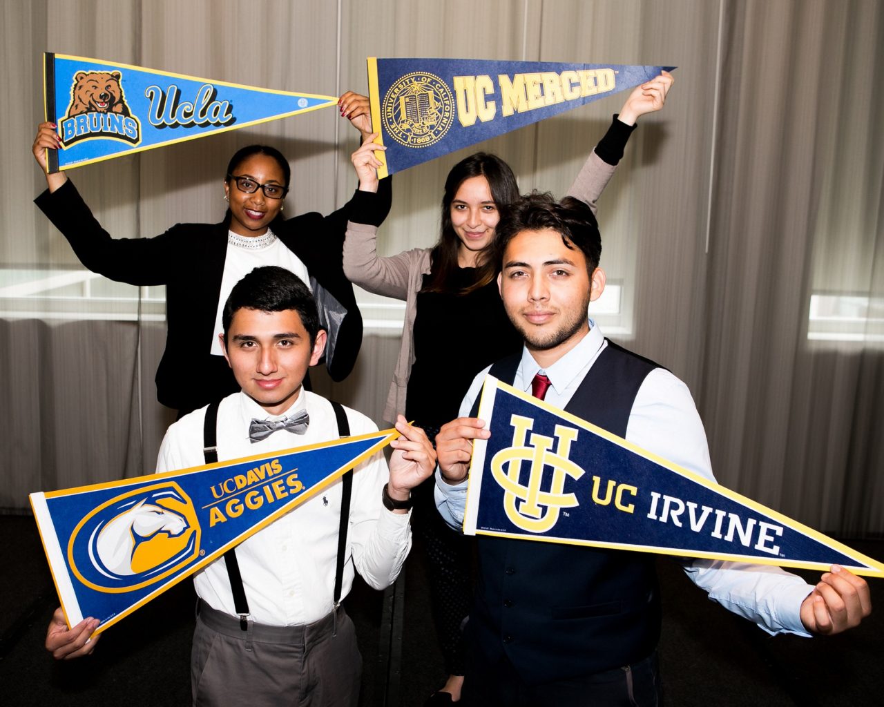 Four of Aspire's Shining Stars graduates holding their college pennants in their hands.